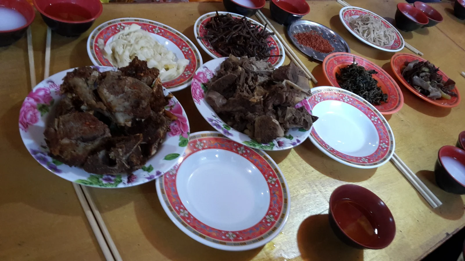 A table of Tibetan-style meat dishes and vegetables photographed in Jiuzhaigou County
