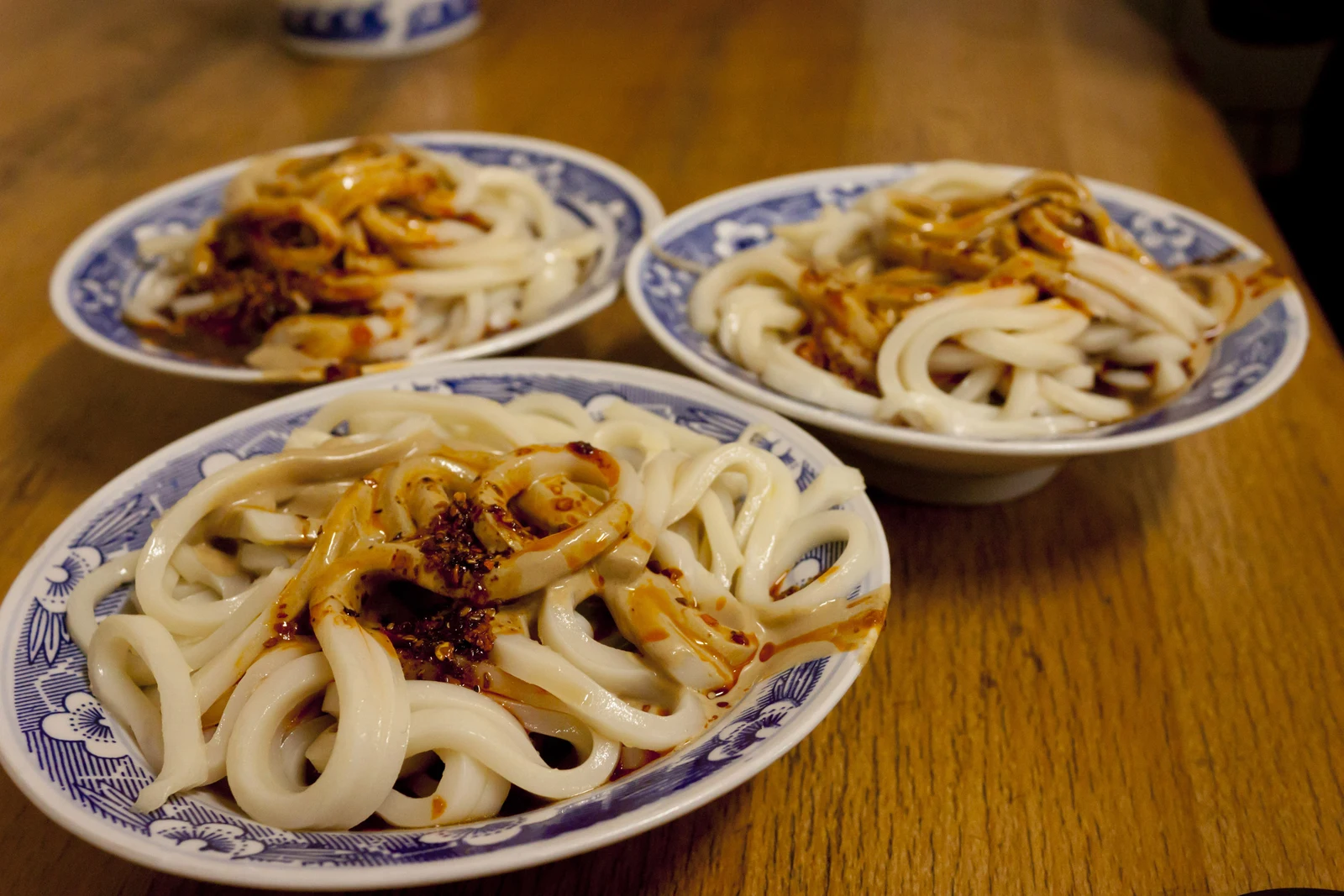 Three small bowls of liangpi cold noodles with a savory dressing