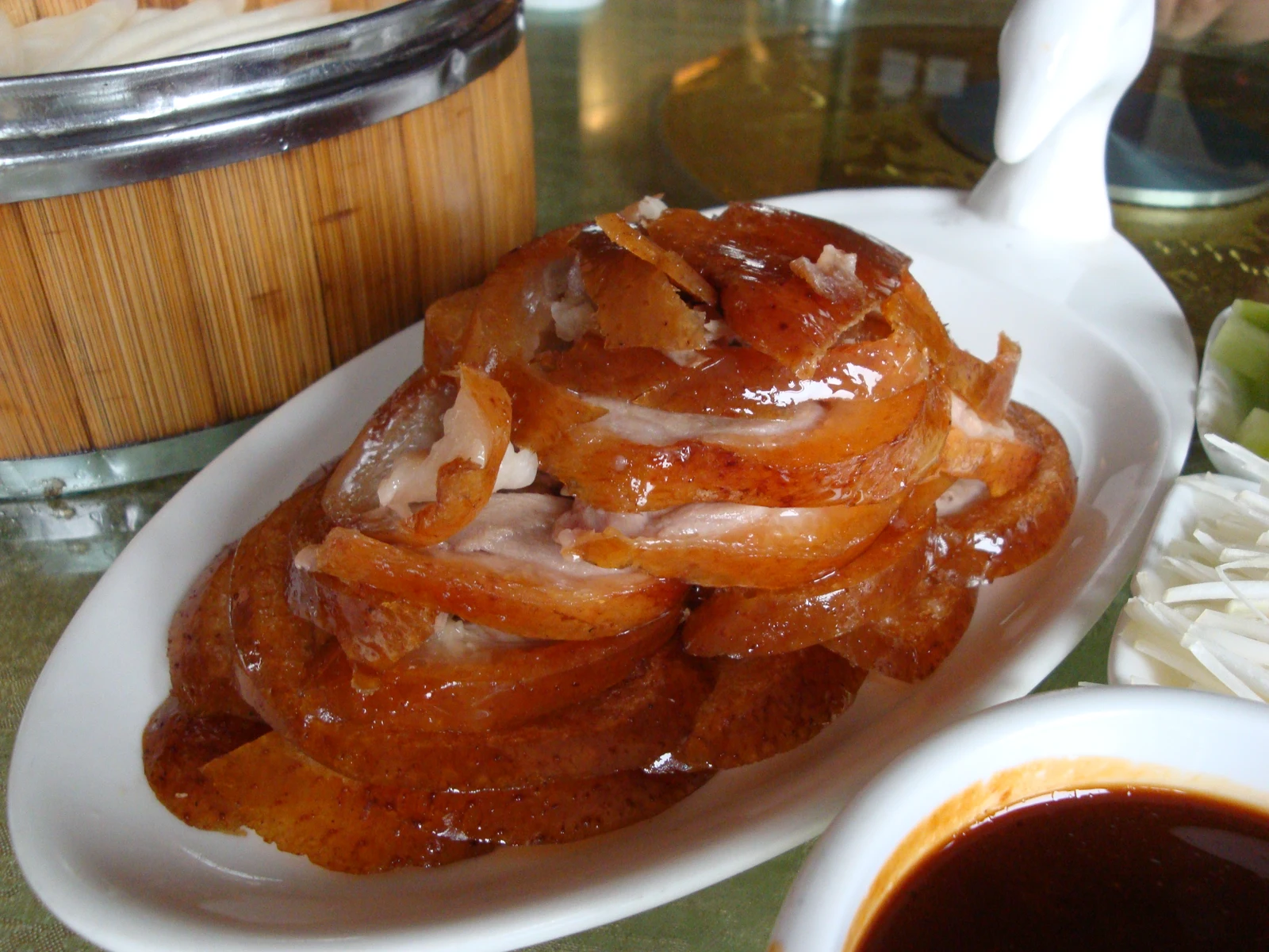 Glossy slices of roast Peking duck arranged on a white platter