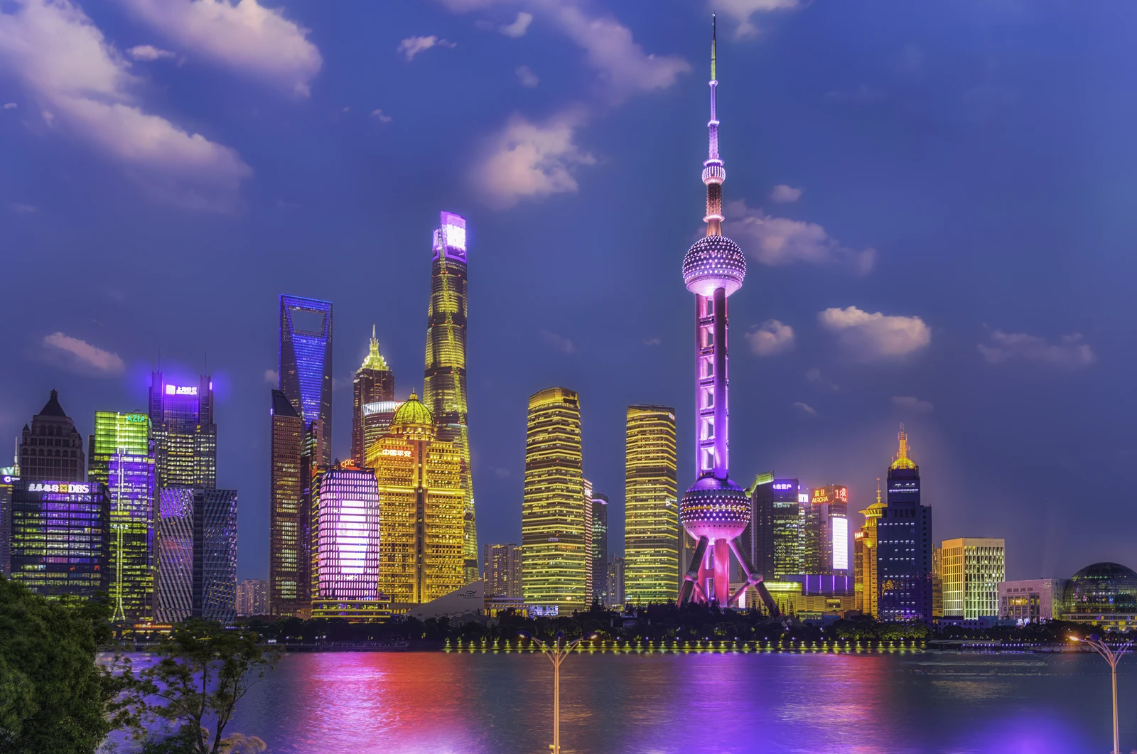 Illuminated Pudong towers and colorful reflections seen from Shanghai North Bund at blue hour